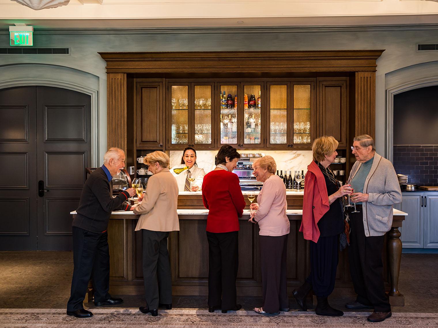 A group of residents enjoy glasses of wine at a bar.